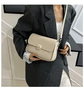 Detail shot of a beige woven square crossbody bag styled with a professional blazer.