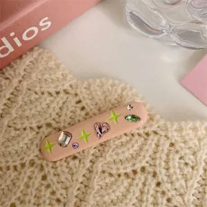 Detail view of pink Y2K hair clip with colorful rhinestones and green stars