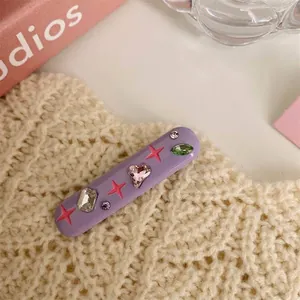 Macro detail of a purple Y2K hair clip featuring colorful rhinestones and pink star patterns