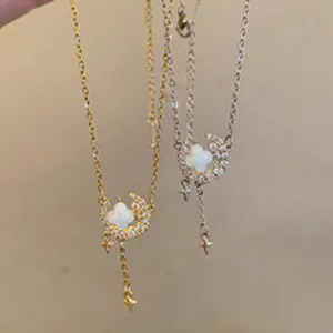 Close-up detail of camellia pearl necklace with crescent moon and star pendants in gold