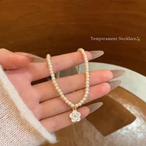 Detail view of an elegant pearl choker necklace featuring a white camellia pendant.