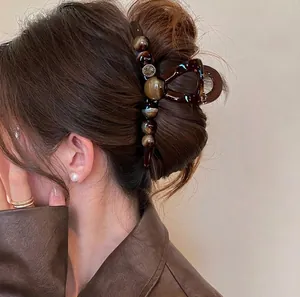 Detail view of a large retro hair claw clip with brown beads on a hair bun