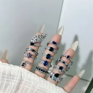 Detailansicht verschiedener silberner Ringe mit blauen Zirkonia auf einer Frauenhand.