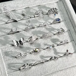 Selection of sparkling silver rings with snake and butterfly designs in a grey tray