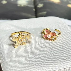 Detailansicht von verstellbaren Ringen mit Blumen und Perlen auf weißem Kasten.