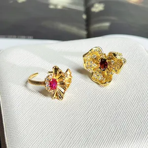 Nahaufnahme von zwei verzierten Goldblumenringen mit rubinfarbenen Edelsteinen.