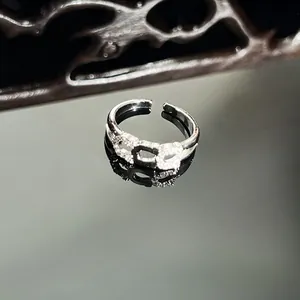 Elegant silver-toned snake ring with micro-pave crystals on dark reflective surface.