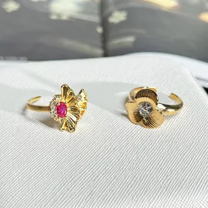 Nahaufnahme von zwei goldfarbenen Blumenringen mit rotem Edelstein und feinen Texturen