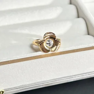 Makroansicht eines goldfarbenen Rings mit dreiblättriger Blume und strukturierter Textur.
