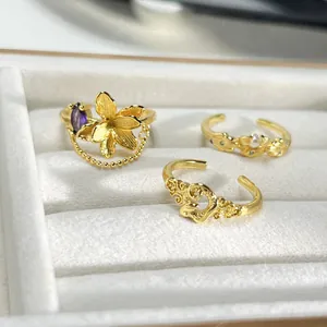 Primer plano de tres anillos dorados vintage con detalles de flores, perlas y borlas