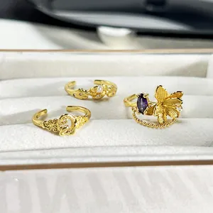 Detalle de los anillos dorados florales con piedra púrpura y perlas