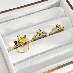 Primer plano de anillos de flores dorados con cadena de borla y perla