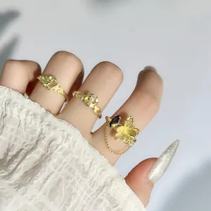 Primer plano detallado de elegantes anillos de flores de oro mate con perla y cadena de borlas