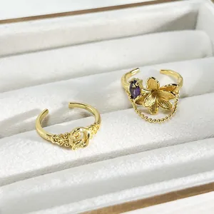 Detalle de anillo dorado con borla de flores y banda abierta cepillada en joyero blanco