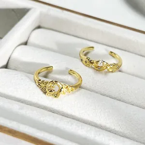 Detalle de elegantes anillos abiertos de oro con flores, corazón y acabado cepillado.