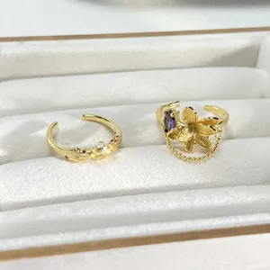 Primer plano anillo flor dorada con piedra púrpura y cadena de borla fina