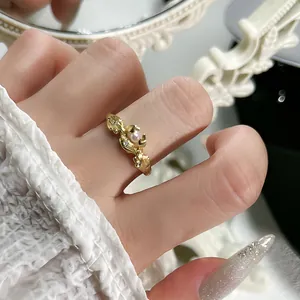 Detalle de primer plano de un elegante anillo abierto dorado con flor y perla fina
