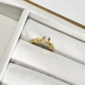 Detalle macro de un anillo abierto dorado texturizado con una perla y pequeños cristales