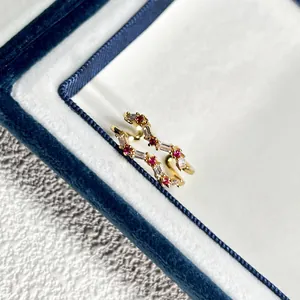 Nahaufnahme eines goldenen Rings mit roten und weißen Zirkonia in einer blauen Box