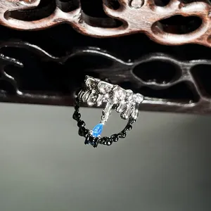 Close-up macro detail of silver lava-style ring with a vibrant blue teardrop gemstone.