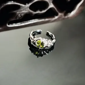 Close-up detail of irregular snake-style silver ring with vibrant green gemstone centerpiece