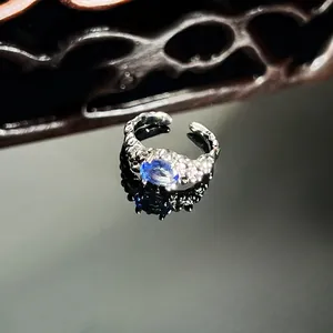 Detailed macro shot of an irregular textured silver ring with oval blue crystal center