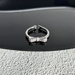 Bague élégante en argent avec nœud et zircones cubiques sur surface réfléchissante noire