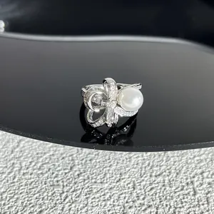 Détail d'une bague nœud argentée avec cristaux scintillants et une grande perle blanche