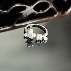 Close-up of an elegant silver-tone open ring with pearls and square cubic zirconia.