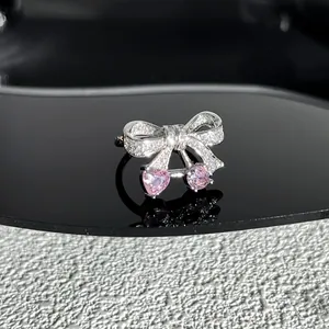 Gros plan sur une bague nœud élégante avec cristaux de cœur roses et micro-pavé