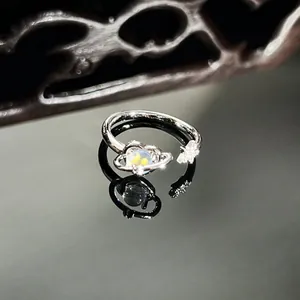 Detailed macro shot of a silver Saturn ring with iridescent opal and star accents
