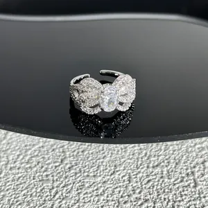 Vue détaillée d'une bague nœud argentée étincelante avec pierre ovale sur surface noire.