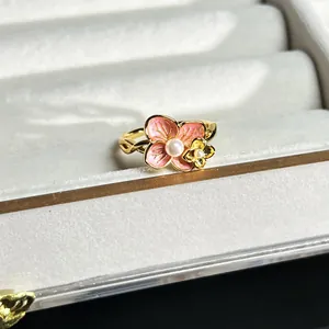 Exquisite Detail eines barocken Gold-Blumenrings mit rosa Blütenblättern und Perle