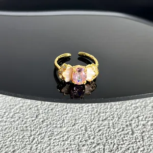 Gros plan d'une bague papillon dorée avec pierre rose ovale et ailes en nacre véritable