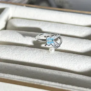 Detailansicht eines eleganten silbernen Schmetterlingsrings mit blauem Glitzer und Perle