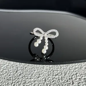 Vue détaillée d'une bague nœud argentée avec pavé de zircons et perles blanches délicates.