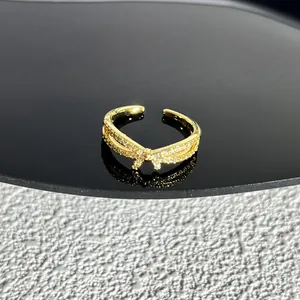 Vue détaillée d'une bague nœud dorée avec pierres scintillantes sur fond texturé contrasté