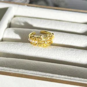 Nahaufnahme eines goldfarbenen Schmetterlingsrings mit filigranen Details und Perlen