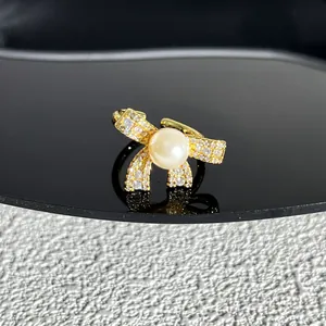 Vue détaillée d'une bague nœud dorée élégante avec perle centrale et pierres brillantes.
