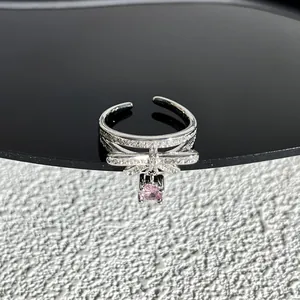 Détail d'une bague nœud papillon argentée avec pierre rose et cristaux pavés étincelants
