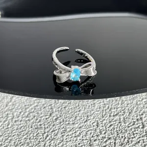 Gros plan sur une bague noeud en argent avec une pierre bleue ovale