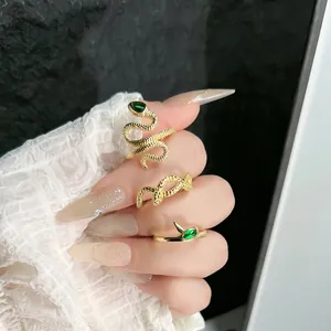 Elegant close-up of golden snake-shaped rings with green gemstones on a manicured hand
