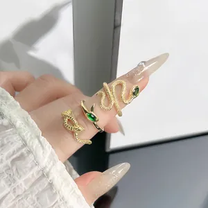 Detail view of three exquisite gold snake rings with green stones worn on model's fingers.