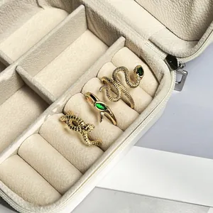 Detail view of gold-toned snake-shaped rings with green stone in a jewelry box