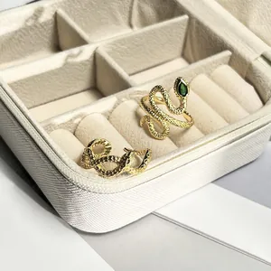 Detailed view of two gold-plated snake rings with green stone in a jewelry box