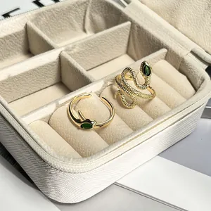 Detail of golden snake-shaped adjustable rings with green gemstone accents in box.