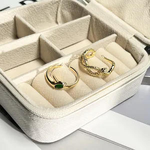 Detail view of two gold snake-shaped adjustable rings in a white textured jewelry box.