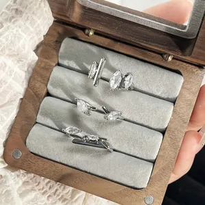 Detailed view of three minimalist marquise zircon open rings inside a wooden jewelry box