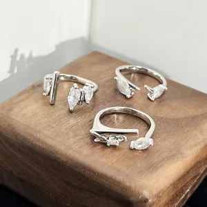 Close-up of minimalist silver rings with marquise-cut cubic zirconia on a wooden base