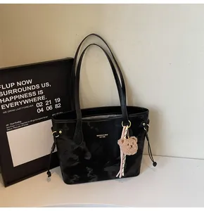Vista detallada del bolso tote grande negro con patrón de mármol y colgante de oso